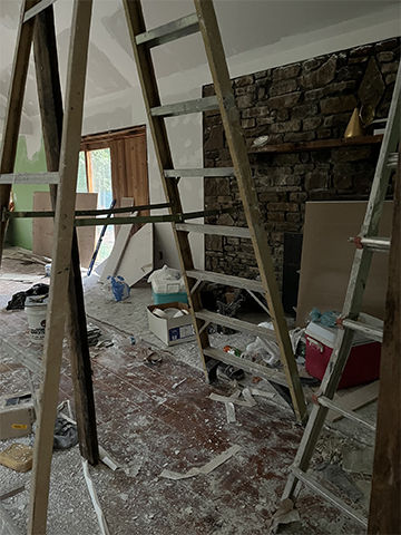 Ladders and building materials around an unfinished fireplace